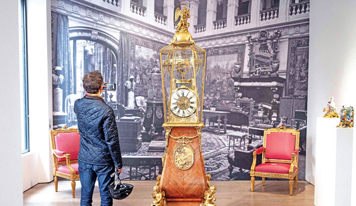 A visitor stands next to an Ormolu Orrery Astronomical Clock with a moving sphere dating back to the Louis XV period on exhibition ahead of its’ auction at the Christie’s auction house in Paris on 13 November 2025. The Louis XV period clock will be auctionned on 18 November 2025 at the Christie’s auction house in Paris. 	PHOTO: AFP